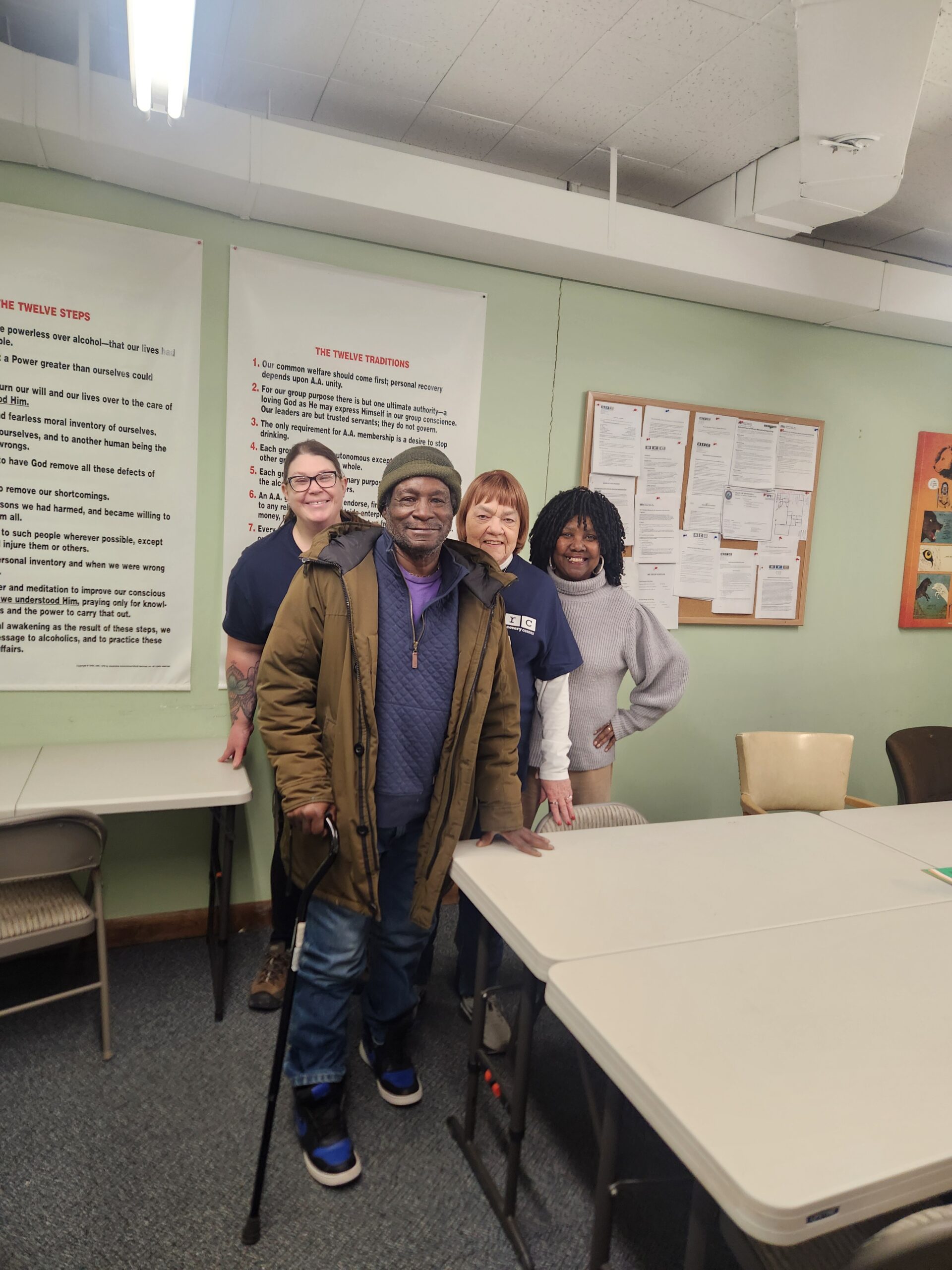 Four individuals pose together in a community space